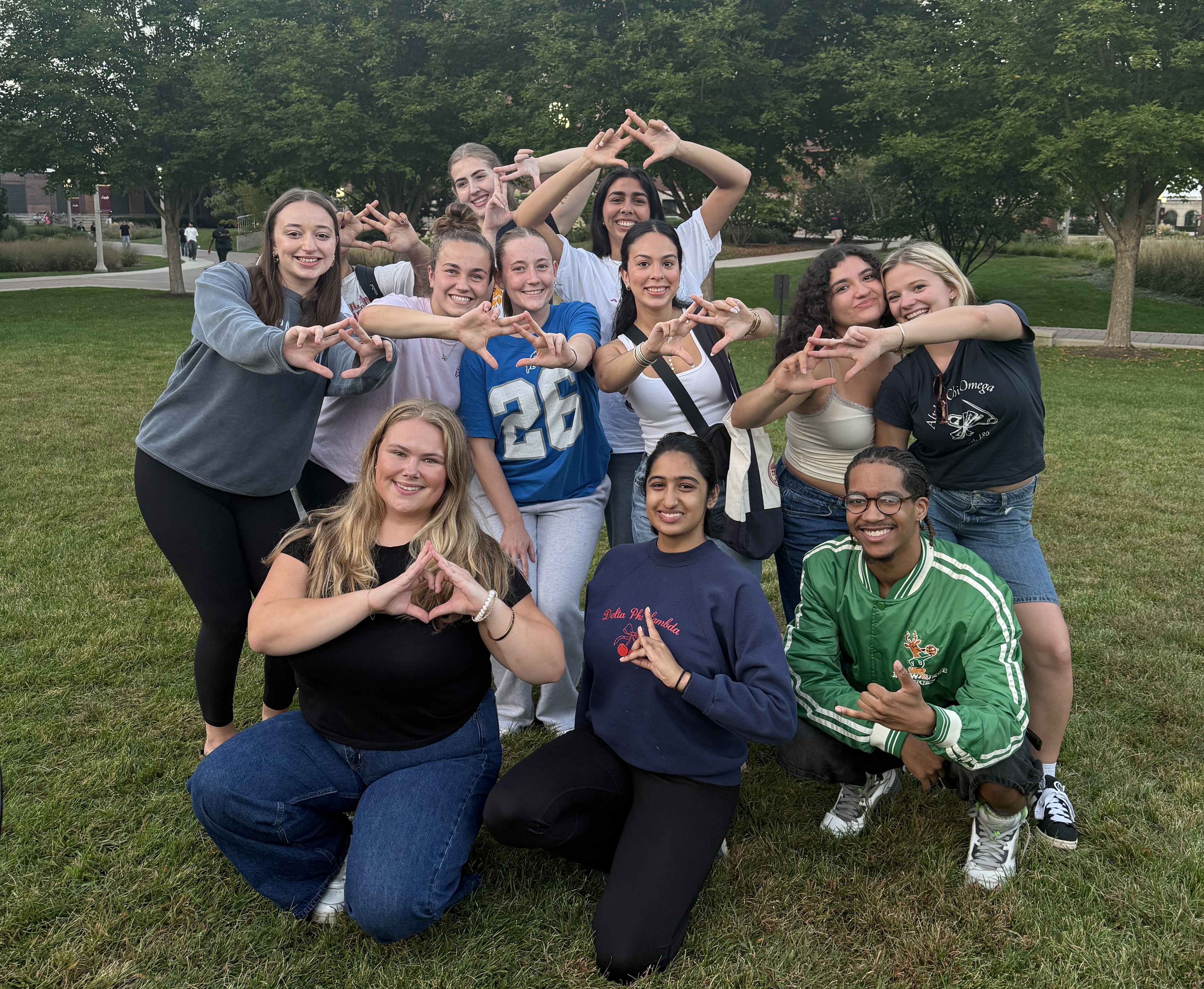 A group of students standing together on grass A group of students standing together on grass